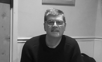 Black and white photo of man with short hair and glasses