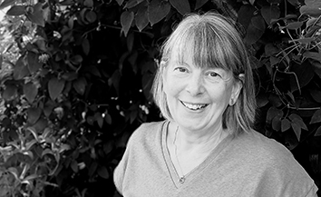 Woman with shoulder length hair and fringe, shrub in background