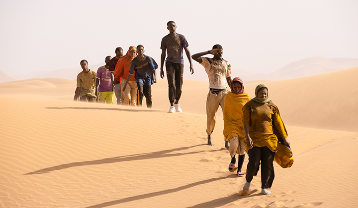 a line of Black people walking through a sandy desert