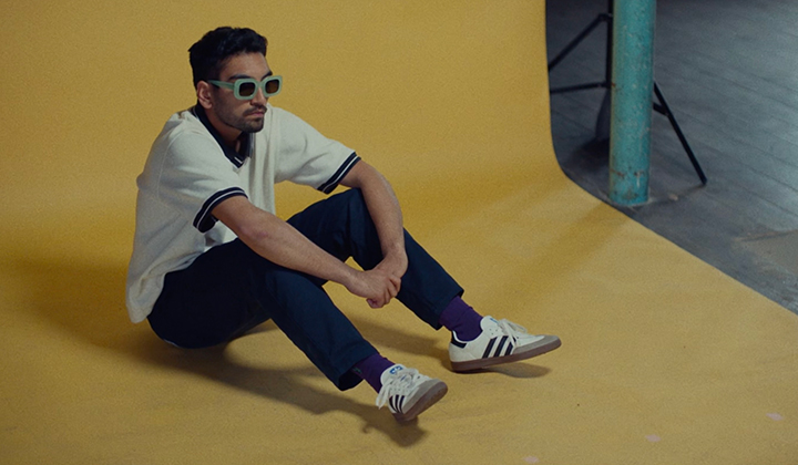 Young Asian man in white t shirt , black trousers and sunglasses sitting on yellow floor