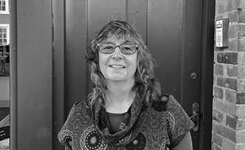 White woman with long curly hair standing in front of door